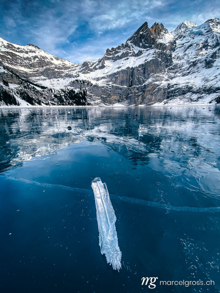 . beautiful icicle on black ice of frozen lake Oeschinensee in the Bernese Alps. Marcel Gross Photography