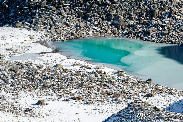 . Türkisfarbener See auf der Macun Seenplatte im ersten Schnee im Herbst. Marcel Gross Photography