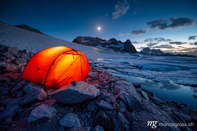 Panorama pictures Switzerland. red tent camping at a glacier lake in the swiss alps. Marcel Gross Photography