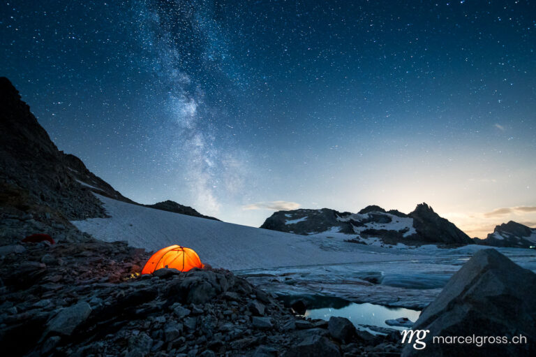 Panoramabilder Schweiz. red tent camping at a glacier lake under the milkyway. Marcel Gross Photography