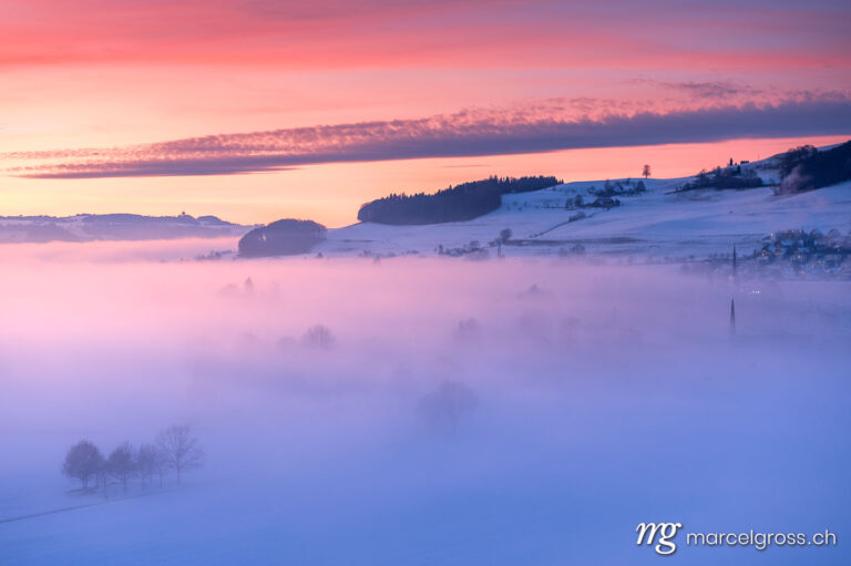 Kitschy winter sunset over Konolfingen with a view of the sea of fog. Taken by Marcel Gross Photography