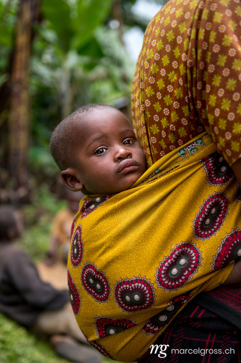 Uganda Bilder. baby in a yellow towel on the back of the mother in southern Uganda. Marcel Gross Photography