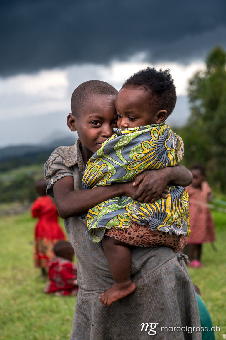 Uganda pictures. Batwa girl with baby in a village near in Mgahinga Gorilla National Park, Uganda. Marcel Gross Photography