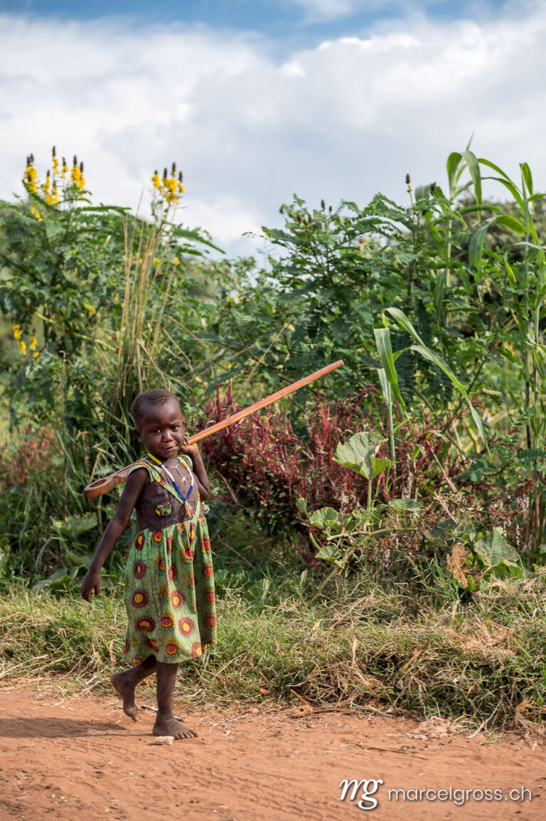Uganda pictures. a karamojong girl walking from the field in the remote Karamoja Region of Uganda. Marcel Gross Photography
