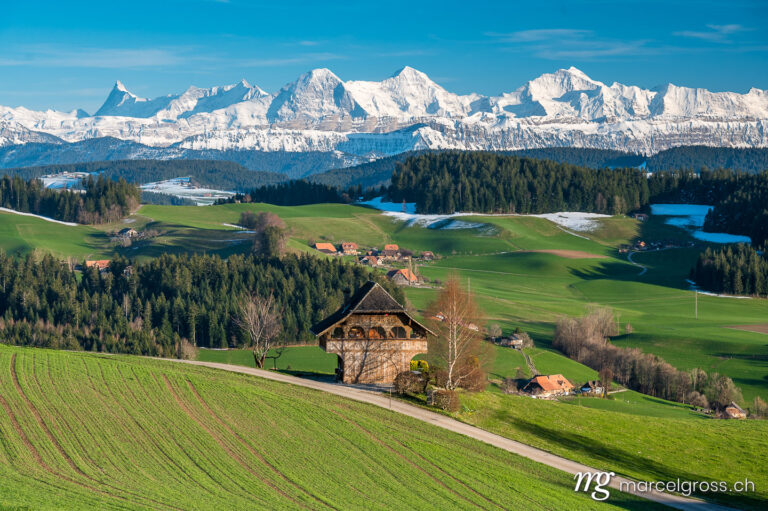 Emmental Bilder. traditional Bernese farmhouse called Stöckli in front of the mighty Bernese Alps in spring. Marcel Gross Photography