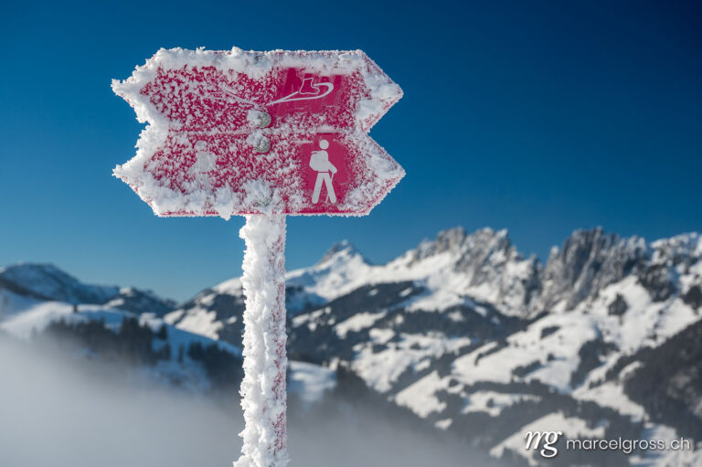 Winterbild Schweiz. frozen winter hiking and snowshoe trail sign in front of Gastlosen, Switzerland. Marcel Gross Photography