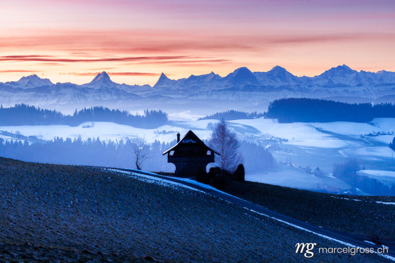 Emmental winter pictures. Emmentaler Spycher in winter in front of the Bernese Alps. Marcel Gross Photography