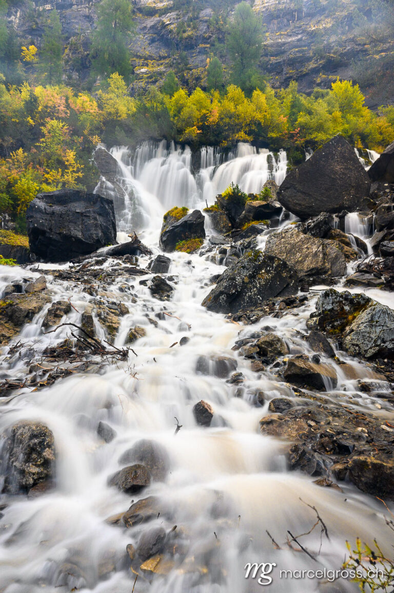 Herbstwasserfall. Sibe Brünne Waterfalls in Lenk in autumn foliage. Marcel Gross Photography