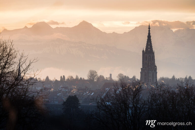 Berner Münster. Altstadt von Bern mit Berner Münster im Morgenlicht mit Eiger, Mönch und Jungfrau im Hintergrund. Marcel Gross Photography